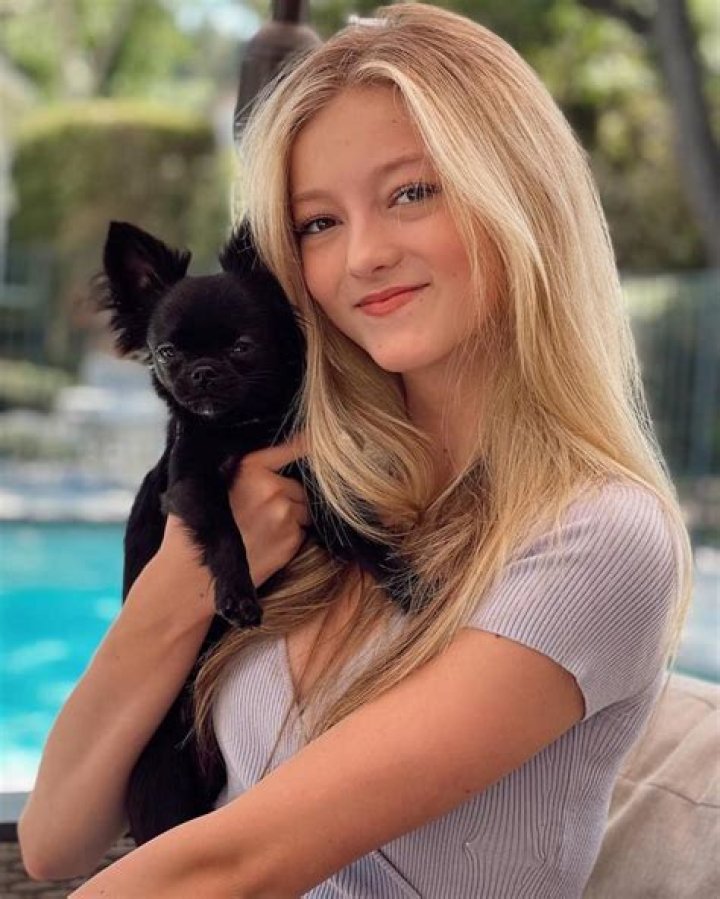 Emily Dobson craddling her dog Harley Dobson as she smiles at the camera.