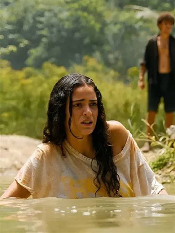 Luna Blaise in a white loose cloth with her father in a brown hat, black t-shirt with a yellow smiley and her mother in a grey cardigan.