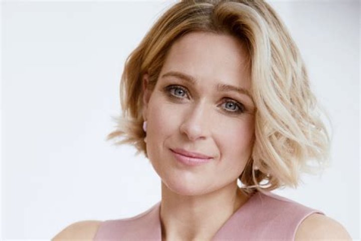Sian Brooke in a blue denim shirt folding her arms.